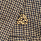 Gold Celtic knot pin on a plaid fabric background