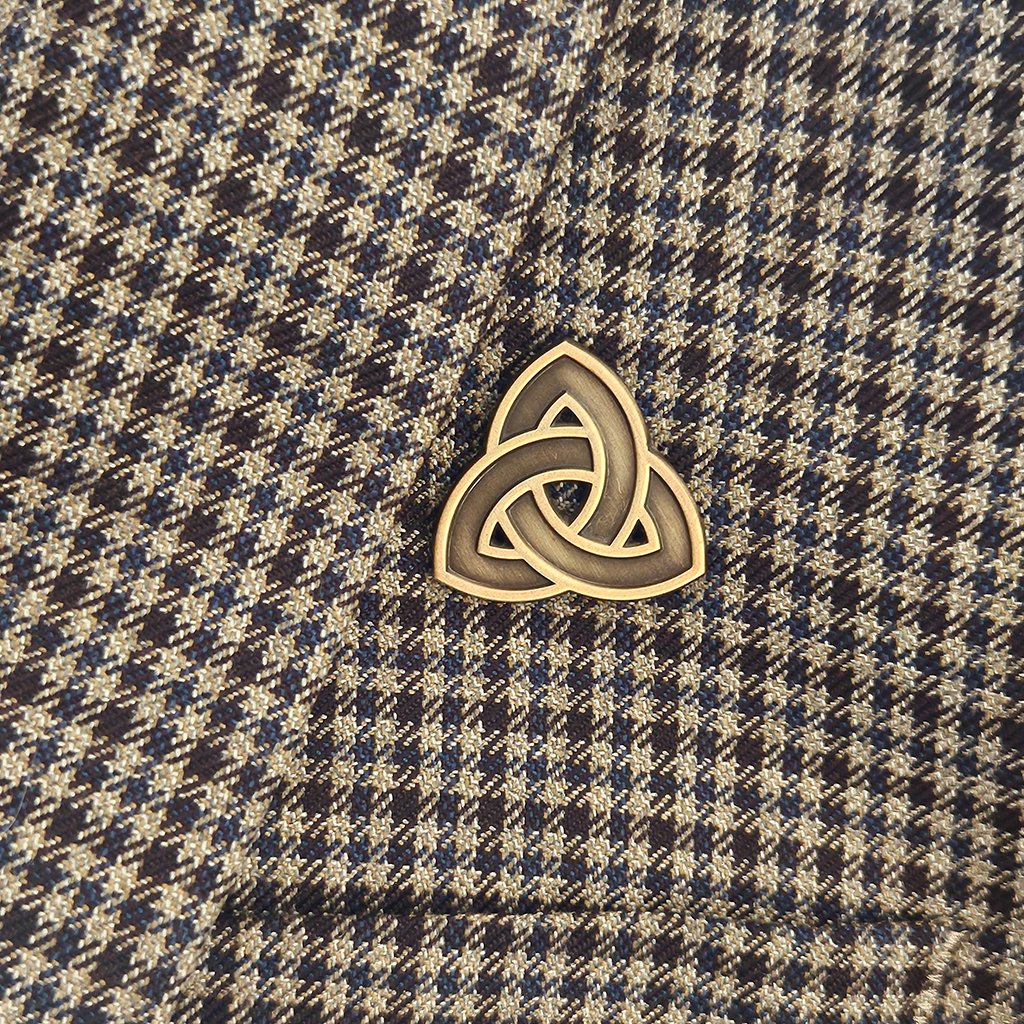 Gold Celtic knot pin on a plaid fabric background