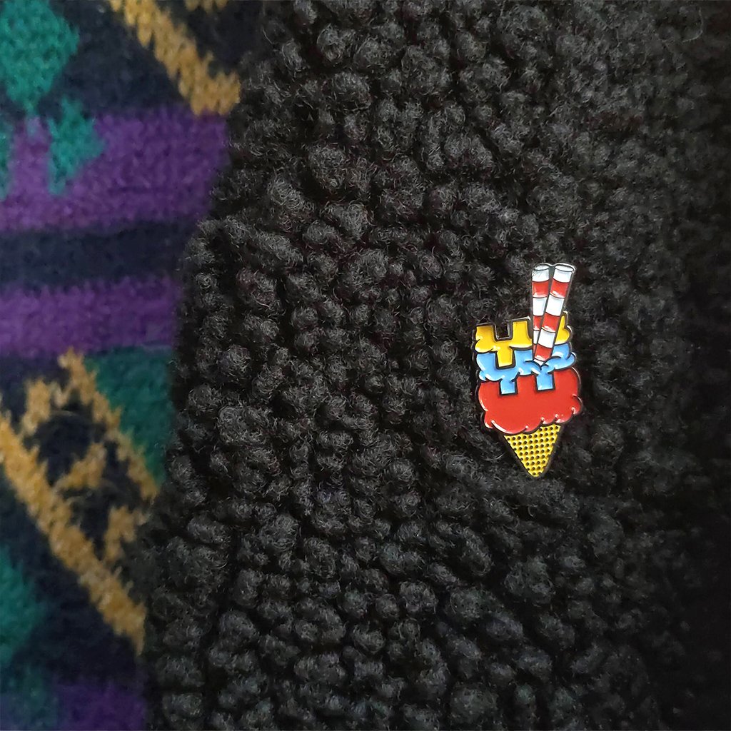 Colorful dublin-themed ice cream cone pin on a textured black surface with a multicolored pattern in the background.