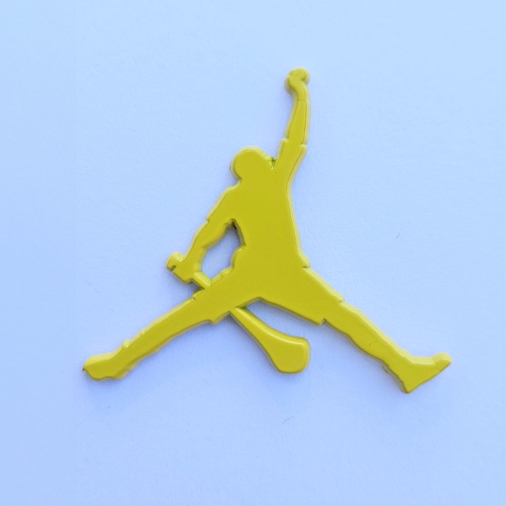 Yellow Hurling GAA pin on a light blue background