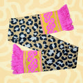 Leopard print scarf with pink tassels and celtic knot on a beige patterned background