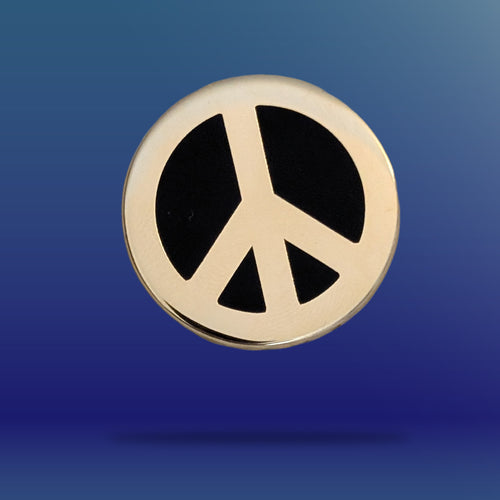 A gold peace sign pin badge against a blue background
