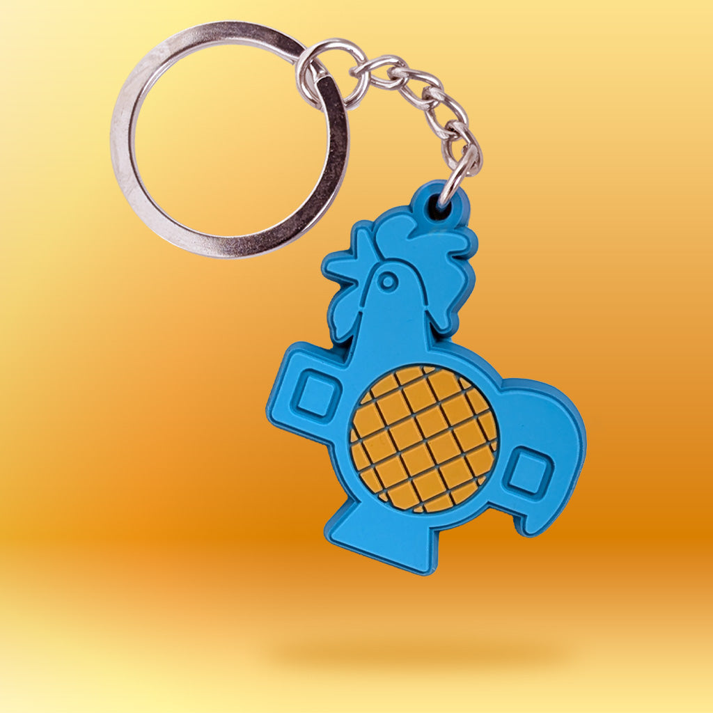 A blue rooster-shaped keychain with a silver metal key ring and chain, shown against a yellow-to-orange gradient background.