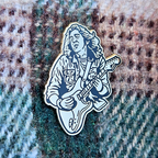 Enamel pin of Rory Gallagher playing guitar on a textured fabric background