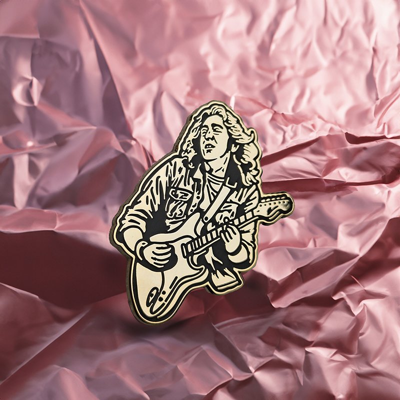 Enamel pin of guitarist Rory Gallagher on crumpled pink paper