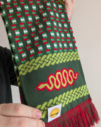 a close-up macro shot of a vibrant and funky scarf that has red, yellow and green colours with a snake and DART motif throughout