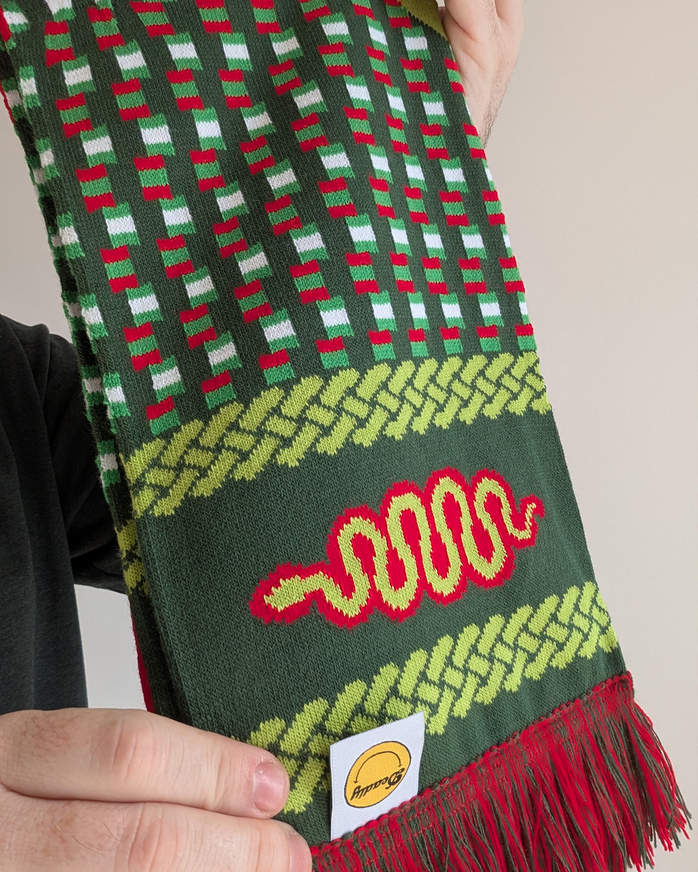 a close-up macro shot of a vibrant and funky scarf that has red, yellow and green colours with a snake and DART motif throughout