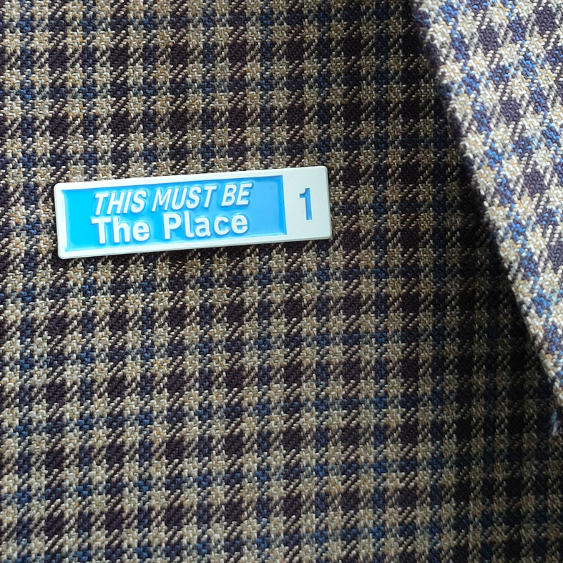 Plaid fabric with a blue and white label reading 'THIS MUST BE The Place'.