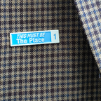 Plaid fabric with a blue and white label reading 'THIS MUST BE The Place'.