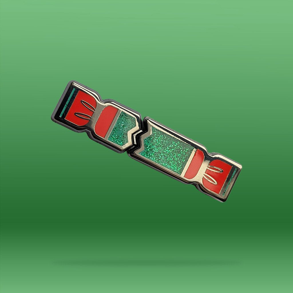 Decorative Christmas Cracker Pin with red and green design on a green background