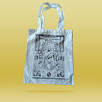 White tote bag with black intricate design depicting the Simpsons book of kells page on a yellow background