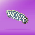 A black and Gold pin that reads 'weirdo' in offset text against a purple background